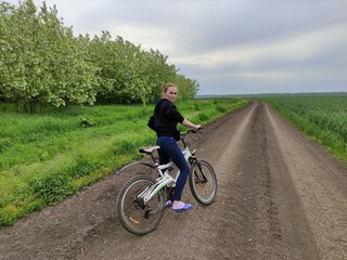 Fototapeta na wymiar Young woman on bike on the field road looking back