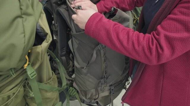 Woman in a store buys a tourist backpack for extreme hiking. Concept of tourism, recreation, travel with a tent and backpack. Hands close up shot