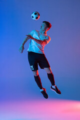 Fototapeta na wymiar Young Caucasian man, male soccer football player jumping isolated on gradient blue pink background in neon light. Back view