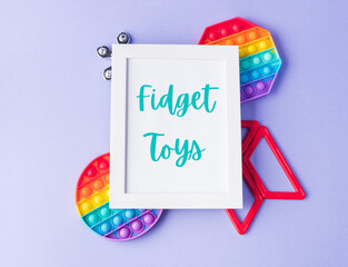 Set of colorful fidget toys for anti stress on purple with text in white frame - obrazy, fototapety, plakaty