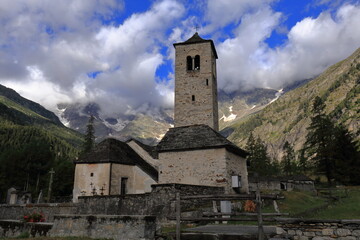Fototapeta na wymiar Chiesa Vecchia a Macugnaga con sfondo di montagne e nuvole n. 2
