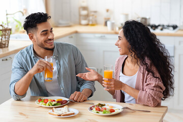 Fototapeta na wymiar Cheerful young arab couple having breakfast together at home