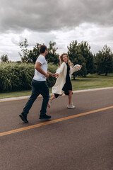 Lovers on the road. The road of the couple in love. The guy leads the girl by the hand. Summer day.