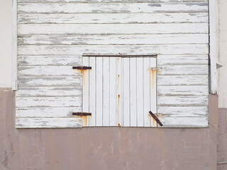 Closed window in old white wooden facade in French West Indies colonial house. Wood slat exterior...