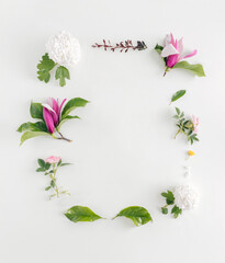 Beautiful spring letter frame made of various flowers. Magnolia, roses, and green leaves on bright background. Minimal nature flat lay copy space.