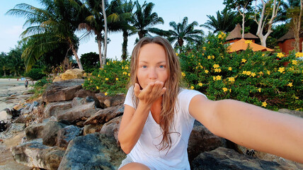 Traveling in Thailand. Pretty young woman in swimsuit taking selfie on the tropical beach.