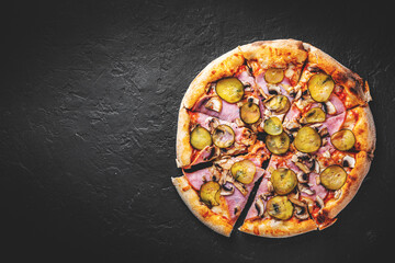 Pizza with Mozzarella cheese, ham, tomato sauce, pepper, pickled cucumbers and mushrooms. Italian pizza on Dark grey black slate background