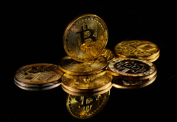 Closeup golden coin with bitcoin logo. Leader in cryptocurrency Bitcoin BTC on a top of coins against black mirror surface. A heap of decentralized digital currency. Crypto payment. Electronic money.