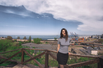 Young brunette in Odessa, Ukraine during sunny weather. Wide angle portrait of young girl during trip in the city near sea.