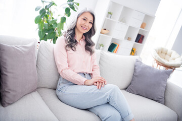 Profile side photo of attractive aged korean woman happy positive smile rest relax weekend sit sofa home