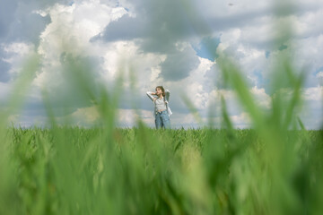 Obraz premium teenage girl in green grass, in the field, against the backdrop of a cloudy sky