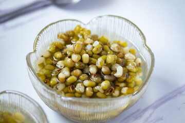 Green beans boiled sugar in a glass cup on a gray background