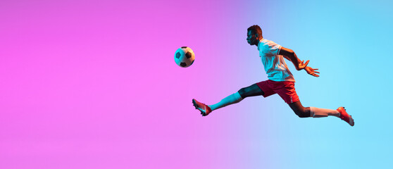 Fototapeta na wymiar Flyer. One African man, professional soccer football player training isolated on gradient blue pink background in neon light.