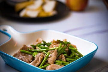 Asparagus sauteed with pork in a white ceramic dish