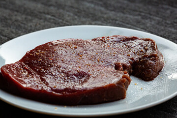 Raw seasoned and salted steak that is resting before being cooked