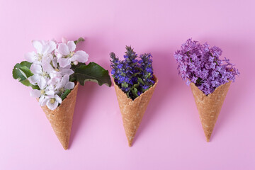 multicolored flowers ice cream in a waffle cup minimalism on a pink background