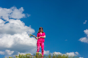 young beautiful girl in pink on a background of clouds in the summer blue sky