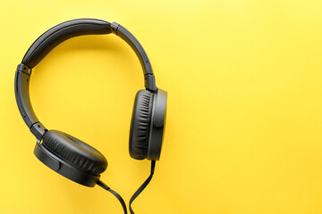 Black wired Headphones on yellow background. Entertainment concept