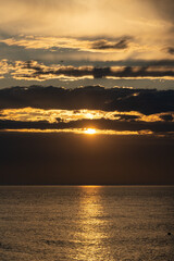Sunset over Black Sea. Close-up. Beautiful multicolored clouds. Sea water glows in rays of setting sun. Atmosphere of tranquility and relaxation. Spring evening in Adler. Soc