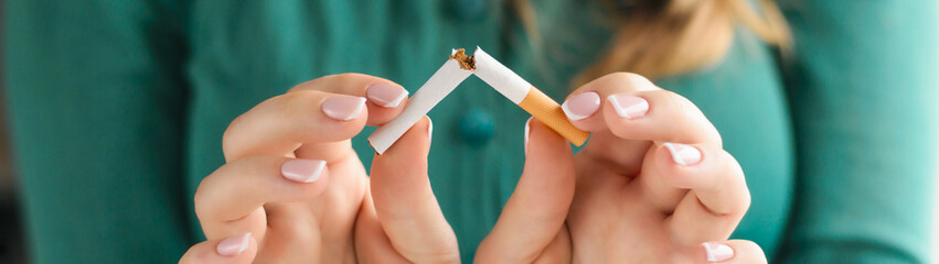 Girl breaks a cigarette as a concept of tobacco addiction panoramic banner