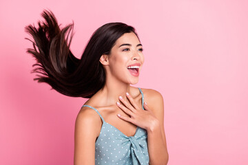 Photo of cheerful amazed young woman look empty space sock fly hair isolated on pink color...