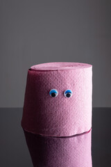 roll of toilet paper with funny eyes on a dark background. Comic concept