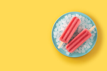 Strawberry popsicles with ice on yellow background. Top view. Copy space