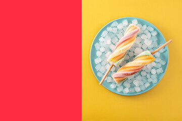Spiral colorful popsicles on red and yellow background. Copy space