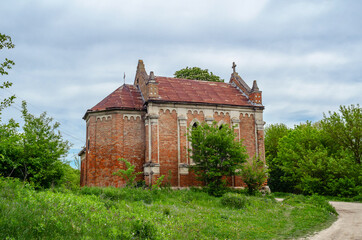 Fototapeta premium Old abandoned church with red bricks on a background of trees