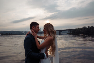 Walk for the newlyweds on the banks of the Dnieper. Photo session by the river. Summer evening.