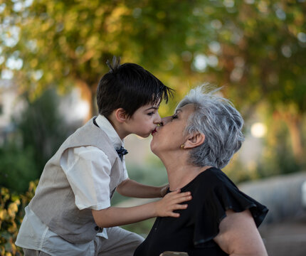 Little boy kisses his grandmother on the mouth in a spring outdoor picture