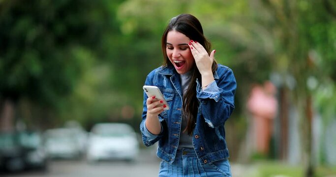 Young woman ecstatic amazing news on phone outside