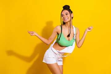 Photo of charming funky dark skin lady wear green crop top smiling dancing isolated yellow color background