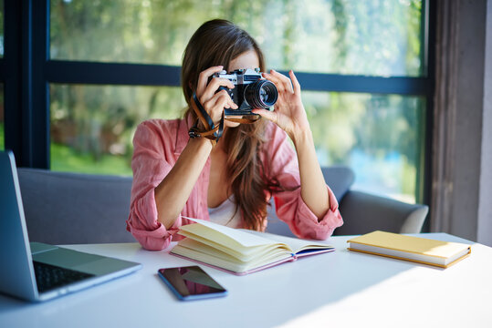 Skilled Female Amateur Testing Vintage Camera During Remote Working At Table Desktop With Laptop Computer And Education Textbook, Professional Journalist Using Retro Technology For Photographing