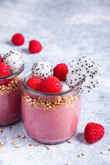 Smoothie with raspberries, banana, pitahaya, quinoa and almond milk in glass jars.