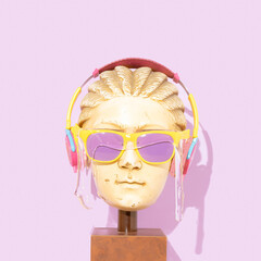 Pop art. Statue head with sunglasses. Trendy summer concept. Colorful sunglasses covered with slime. Pink headphones. On pastel purple background.