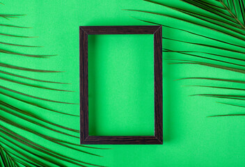 Green background with picture frame and palm leaves. Flat lay template. Minimalist summer backdrop with copy space