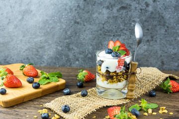 Bowl of homemade granola with Greek yogurt and fresh berries mix on wooden background from top view. Healthy blueberry and Strawberry parfait in a jar.