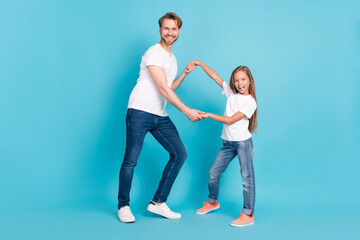 Full body portrait of two positive persons hold arms dancing look camera isolated on blue color background