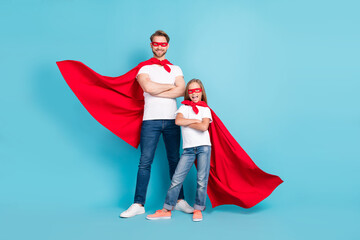 Full length portrait of two confident persons folded arms wear red hero costume isolated on blue...