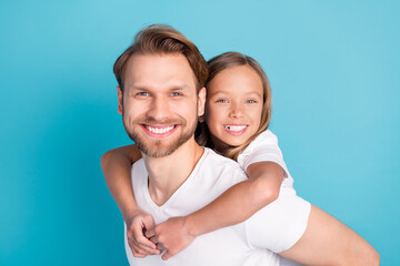 Photo of two cheerful candid persons beaming smile look camera piggyback isolated on blue color background