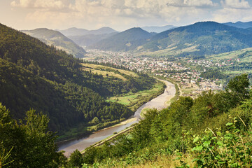 Mountain landscape with river and village views. Carpathians