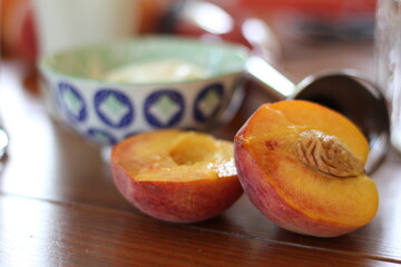 peach and pit split in half next to bowl