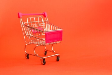 Mini shopping cart or trolley isolated on red background with copy space.