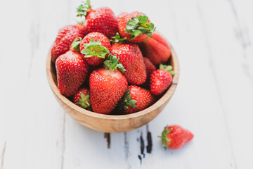 Strawberries in wooden bowl on green background