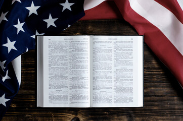 Open book Holy Bible on a wooden background. United States of America flag. Desktop.