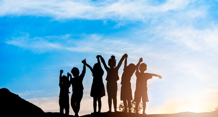 Silhouette back view refugee kid group playing in sunset.Kid child boy and girl worship.Raised...