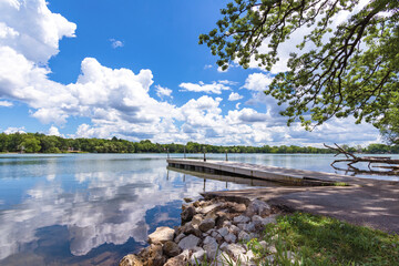 Looking at the boat launch on Genesee Lake in Waukesha County, Wisconsin.  Lazy cumulus clouds are reflected in the calm lake waters.