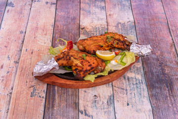 Chicken thighs cooked in tandoori style on top of boiling plate with aluminum foil on the edges of...
