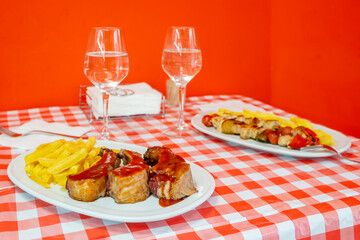 roasted pork ribs with barbecue sauce and potatoes on a restaurant table with a  set up for two people